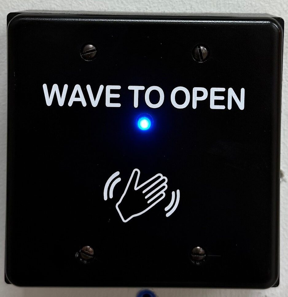 Wave-to-open touchless door actuator on a commercial doorway